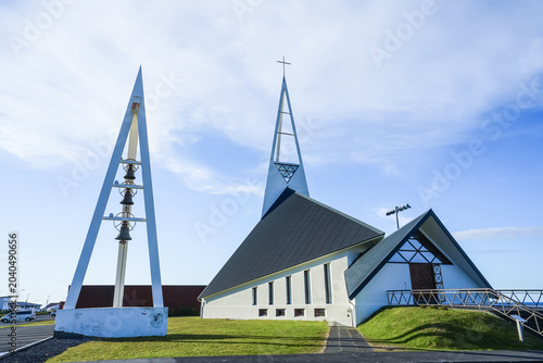 Photos Modern church with distinctive triangular architecture and bell tower under a cl
