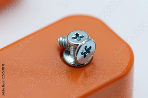 A screw is sitting on top of an orange box