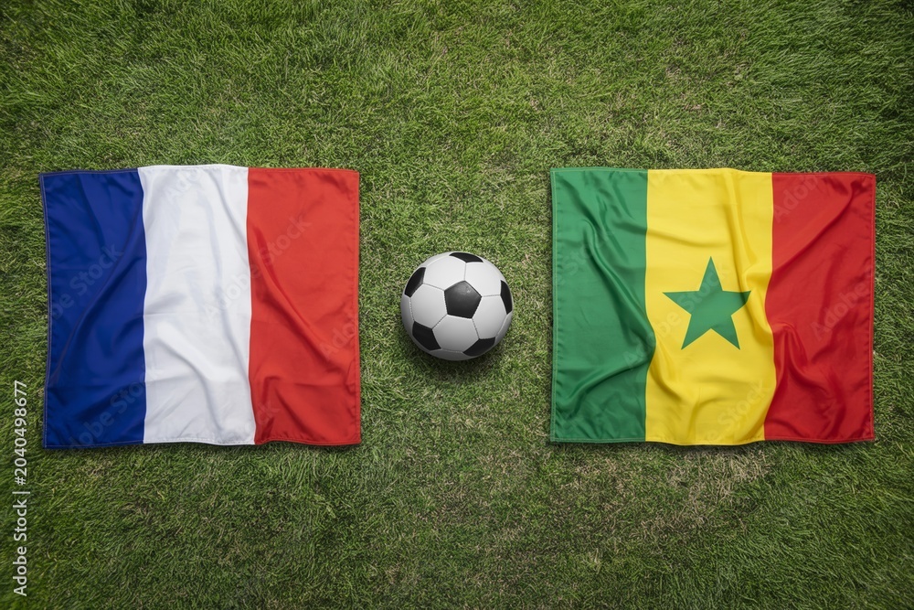 Naklejka premium France and Senegal national flags displayed on a vibrant green grass field with a soccer ball