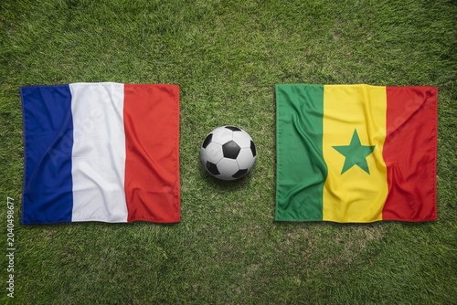 France and Senegal national flags displayed on a vibrant green grass field with a soccer ball