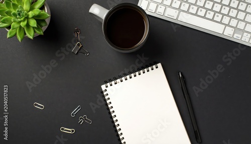 Workspace with coffee, notepad, pen, keyboard, and succulent plant on black surface.
