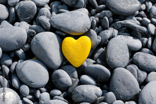 Yellow heart on stone among gray pebbles