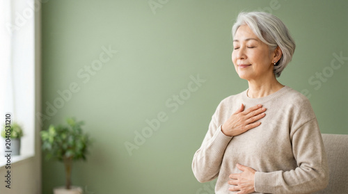 穏やかな時間を楽しむ70代日本人女性のウェルネスイメージ。
淡いグリーン背景と自然光が健康的で安心感のある雰囲気を演出。
健康寿命やアクティブシニア、長寿社会のテーマに最適。