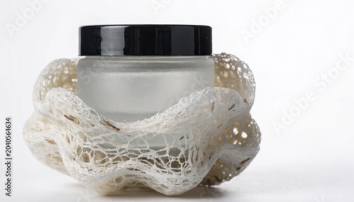A natural piece of netting elegantly surrounds a clear cosmetic product jar on a clean white