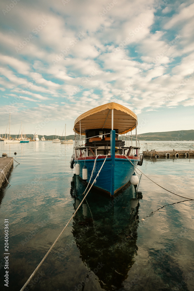 Obraz premium Vintage rowboat moored at a marina coastline during a golden hour evening sunset.