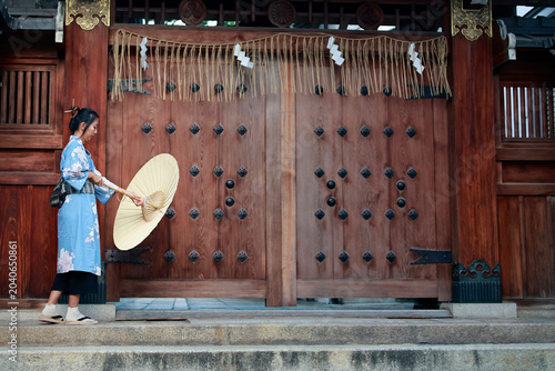 Young Woman in Blue Kimono Holding Paper Umbrella at Japanese Shrine Gate