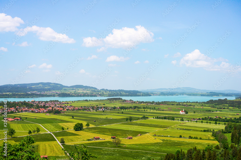 Obraz premium Scenic Bavarian landscape with a village nestled beside a tranquil lake and rolling green fields