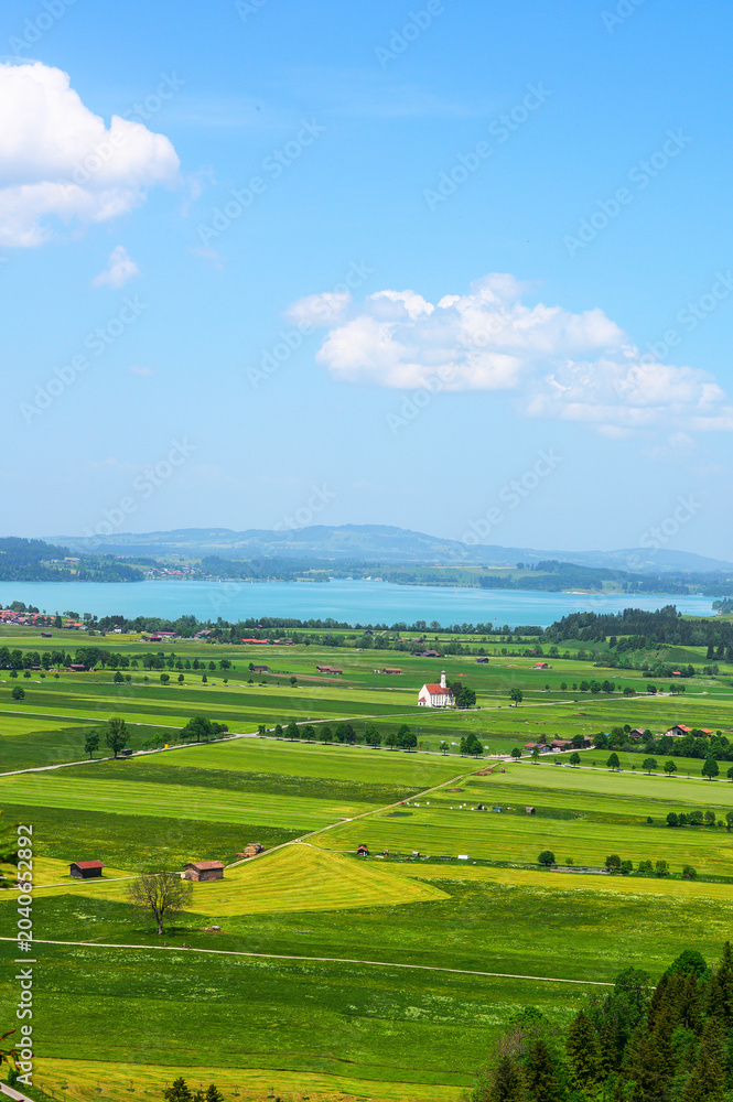 Obraz premium Scenic Bavarian landscape with a white church and turquoise lake under a blue sky