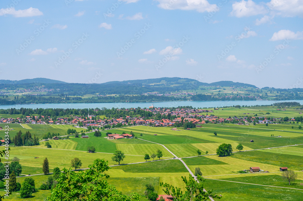 Obraz premium Scenic Bavarian village nestled beside a tranquil lake with rolling green hills