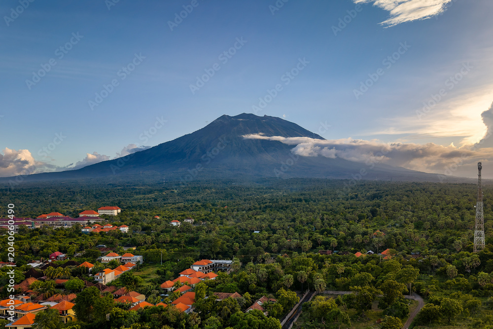 Obraz premium Mount Agung volcano towering over a lush tropical forest and village in Bali