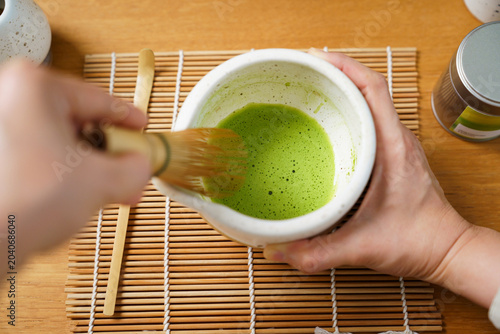 Preparing traditional Japanese matcha green tea with a bamboo Chasen