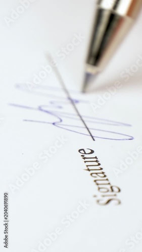 Vertical signature signing on document. Close-up shot shows pen writing signature on paper. Professional atmosphere highlights importance of legal agreements.