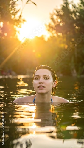 A woman in a serene lake at sunset