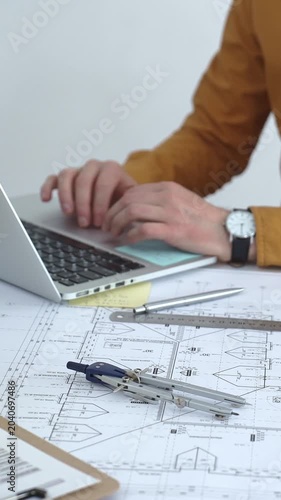 Architect working on new building development project, planning blueprints and collaborating on construction plans using a laptop and architectural models