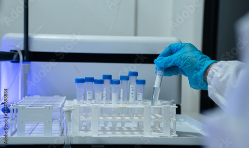 Lab work, scientists holds a test tube takes the test from a test tube in analysis for vaccine development.