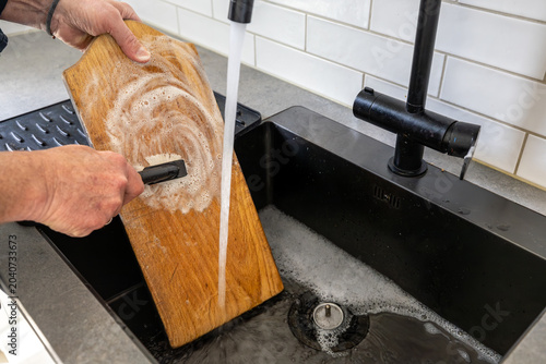 Canvas Print Stockholm, Sweden A man scrubs a wooden kitchen cutting board with soap and water