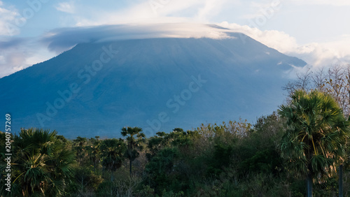 Foto Volcanic mountain rising above tropical forest under cloudy sky in Bali