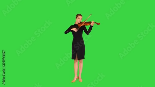 Charming young woman in black dress plays the violin on a Green Screen, Chroma Key.