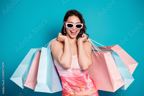 Fényképezés Happy young woman carrying pastel shopping bags, wearing pink sunglasses and a f