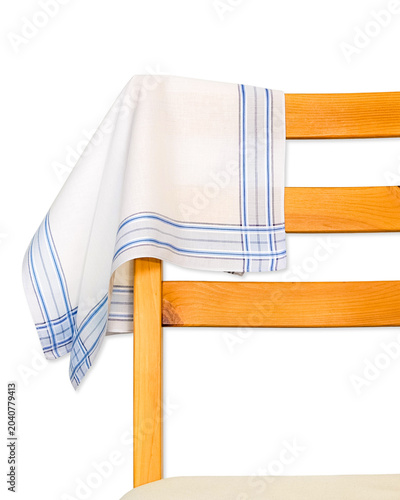 A classic white cotton handkerchief with thin blue striped borders draped over the back of a wooden chair isolated on a white background.
