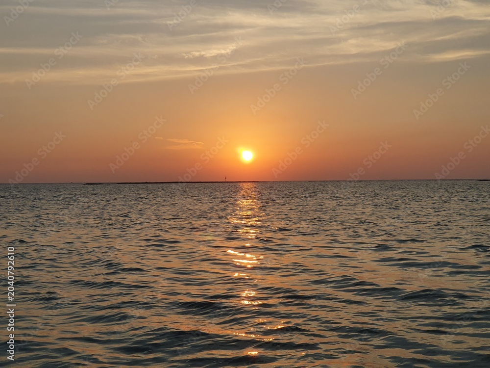 Fototapeta premium Beautiful golden sunset over the calm ocean horizon with sun reflection on water