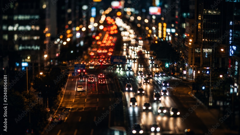 Obraz premium A long-exposure capture of highway traffic at night, showing blurred light trails from moving vehicles against a backdrop of city buildings