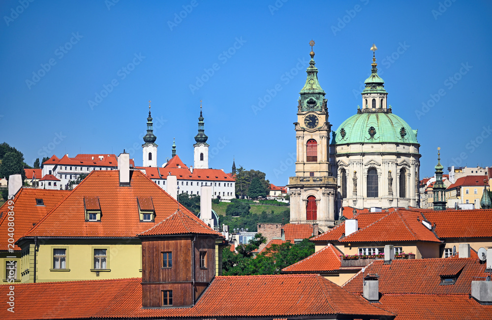 Obraz premium St. Nicholas Church and Strahov Monastery Rising Above Red Rooftops in Prague