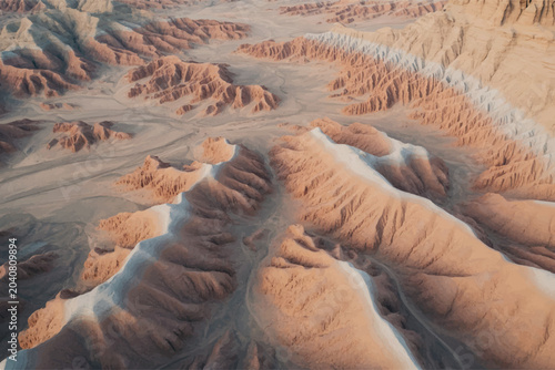 Fotografie Aerial view of a sprawling desert landscape featuring winding canyons and eroded badlands formations at sunset