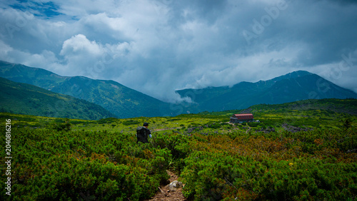 Tableau sur toile Lone hiker approaching a mountain hut across an alpine plateau Japan