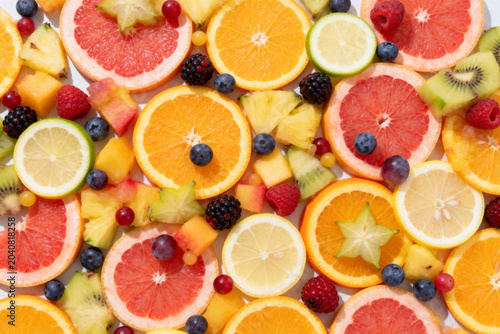Assorted sliced citrus fruits and mixed berries on white background