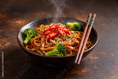 Hot Asian Noodles with Broccoli, Red Chili, and Sesame Seeds in Bowl with Chopsticks