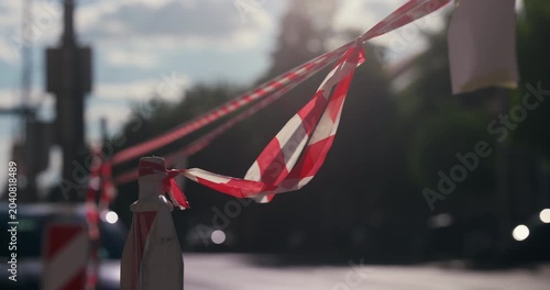 Red and white safety tape stretched across a city street on a sunny day during Labor Day holiday.