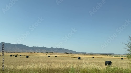 Driving plate view of Kyrenia mountain range known as Girne or Besparmak in Cyprus. Countryside rural summer field landscape with wrapped round hay bales details.