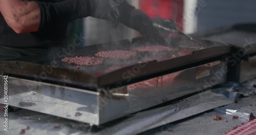 Burger patties cooking on a flat top grill at Kvatric Market during Labor Day holiday.