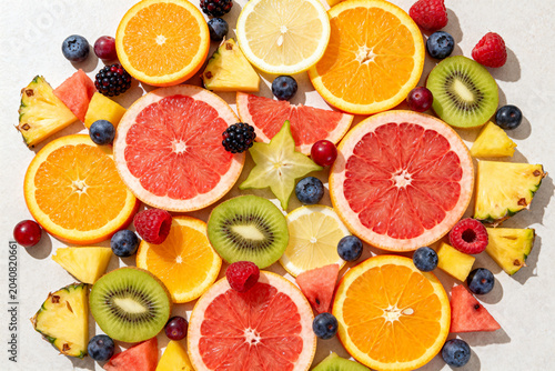 Assorted fresh sliced citrus and tropical fruits on light background