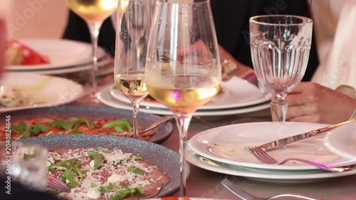 Selective focus on wineglasses with blurred hand serving food at a wedding reception table