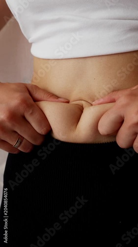 Woman checking belly fat during weight loss and body transformation journey.