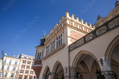 Historic building stands under clear blue sky in a busy town square during daytime in a European city. Cloth Hall, Krakow. Interior of the Cloth Hall. Vault.