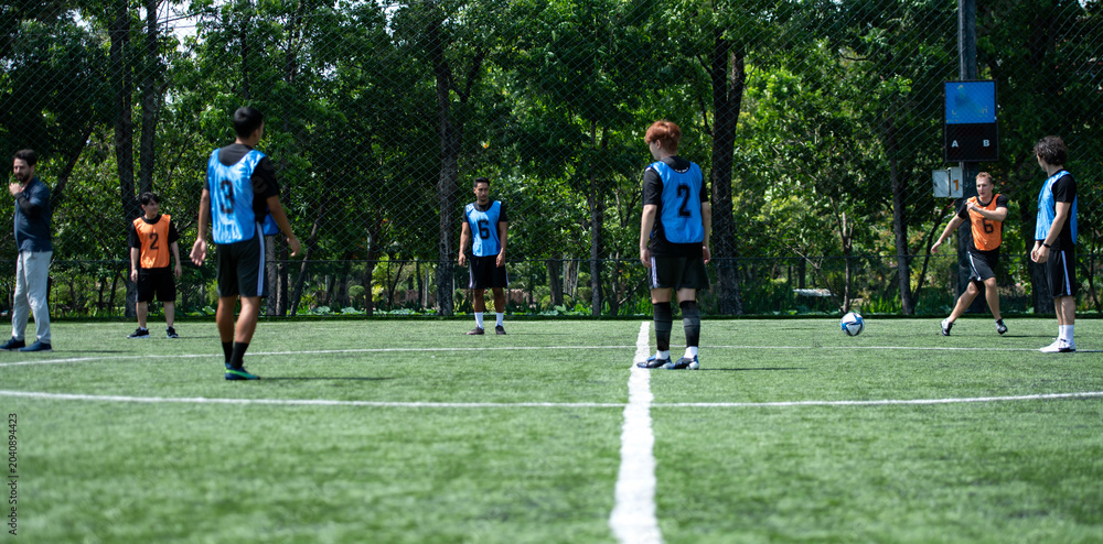 Obraz premium Soccer coach leading a practical training drill with players on an outdoor football field