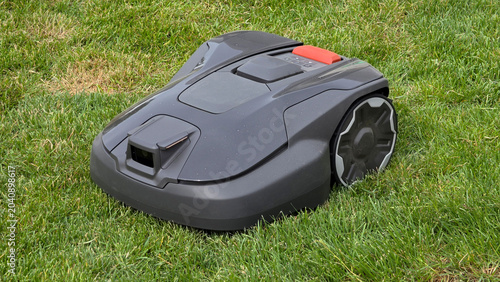 Tableau sur toile Modern dark gray robotic lawn mower with a built-in camera cutting lush green gr