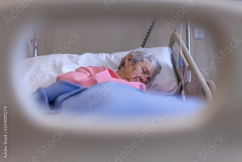 Billede på lærred Elderly Woman Patient Sleeping In Hospital Bed Healthcare Crisis Senior Care Med