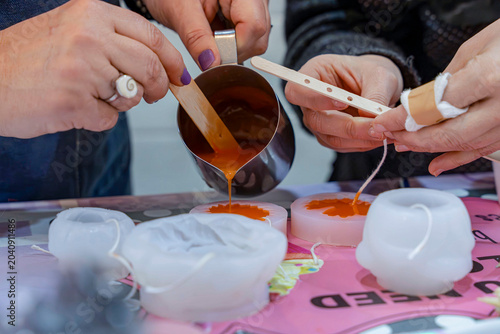 Фотография Hands pouring melted wax during candle making workshop