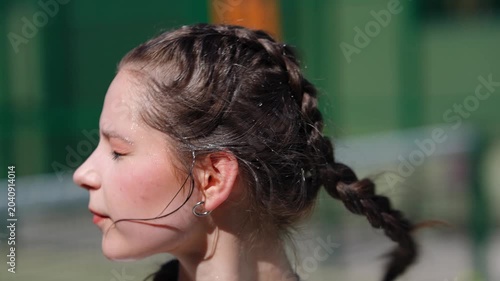 Beautiful exhausted teenage girl wiping sweat from her forehead after a workout. Portrait of an athlete resting under the sun outdoors