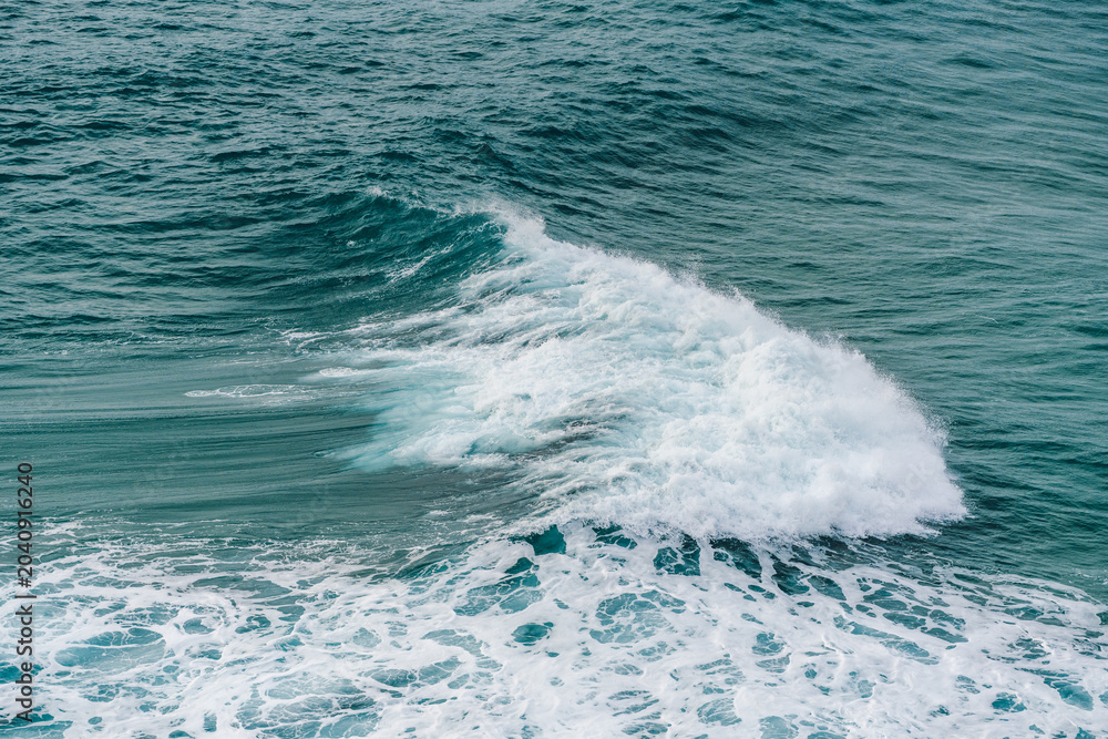 Naklejka premium Ocean wave breaks in a smooth curve with white foam