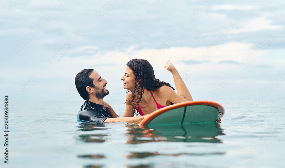 Obraz premium Portrait of a young couple surfing at the beach, holding surfboards, having fun together ocean waves, healthy life holidays adventure concept