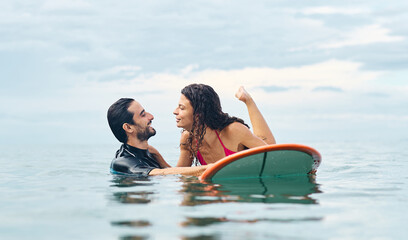 Portrait of a young couple surfing at the beach, holding surfboards, having fun together ocean waves, healthy life holidays adventure concept
