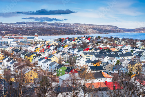 Colorful houses in Kirkenes in Norway near the water with mountains in the background during the day