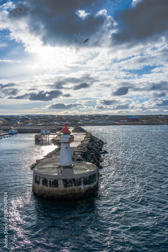 Lighthouse of norwegian town Vardo with blue sea and clouds in the background