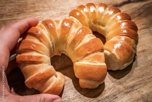 Fresh Golden Crescent Bread Rolls on Rustic Wooden Table.  Freshly baked golden crescent bread rolls with a glossy crust arranged on a rustic wooden tabletop. Warm natural tones, artisan bakery style.