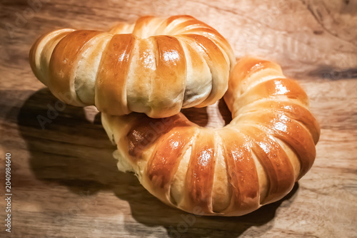 Fresh Golden Crescent Bread Rolls on Rustic Wooden Table.  Freshly baked golden crescent bread rolls with a glossy crust arranged on a rustic wooden tabletop. Warm natural tones, artisan bakery style.